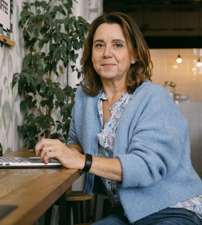 Overgangscoach Anke Lahaije, zittend aan een bureau met haar laptop voor zich.