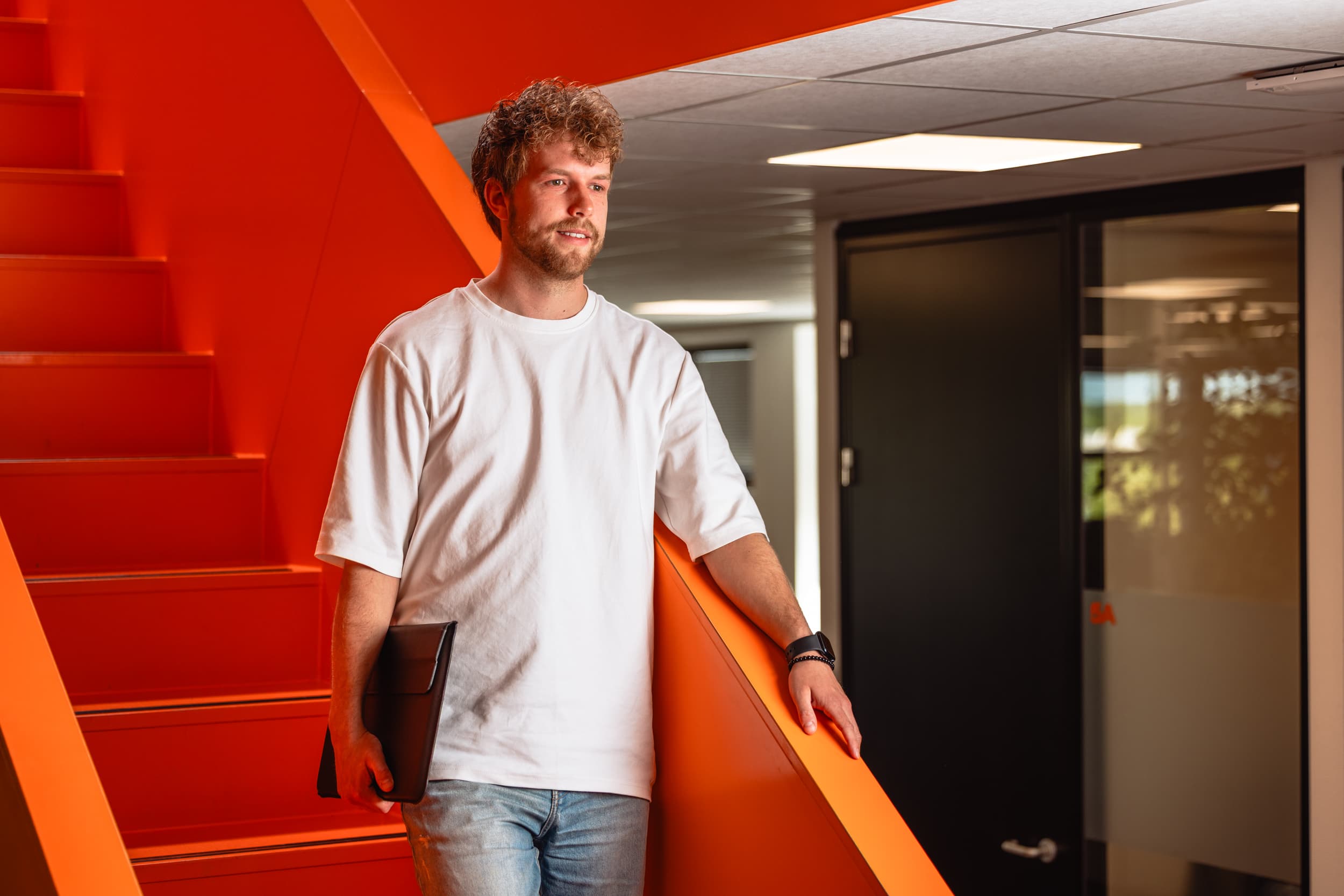 Collega met ipad onder zijn arm loopt van een fel oranje trap